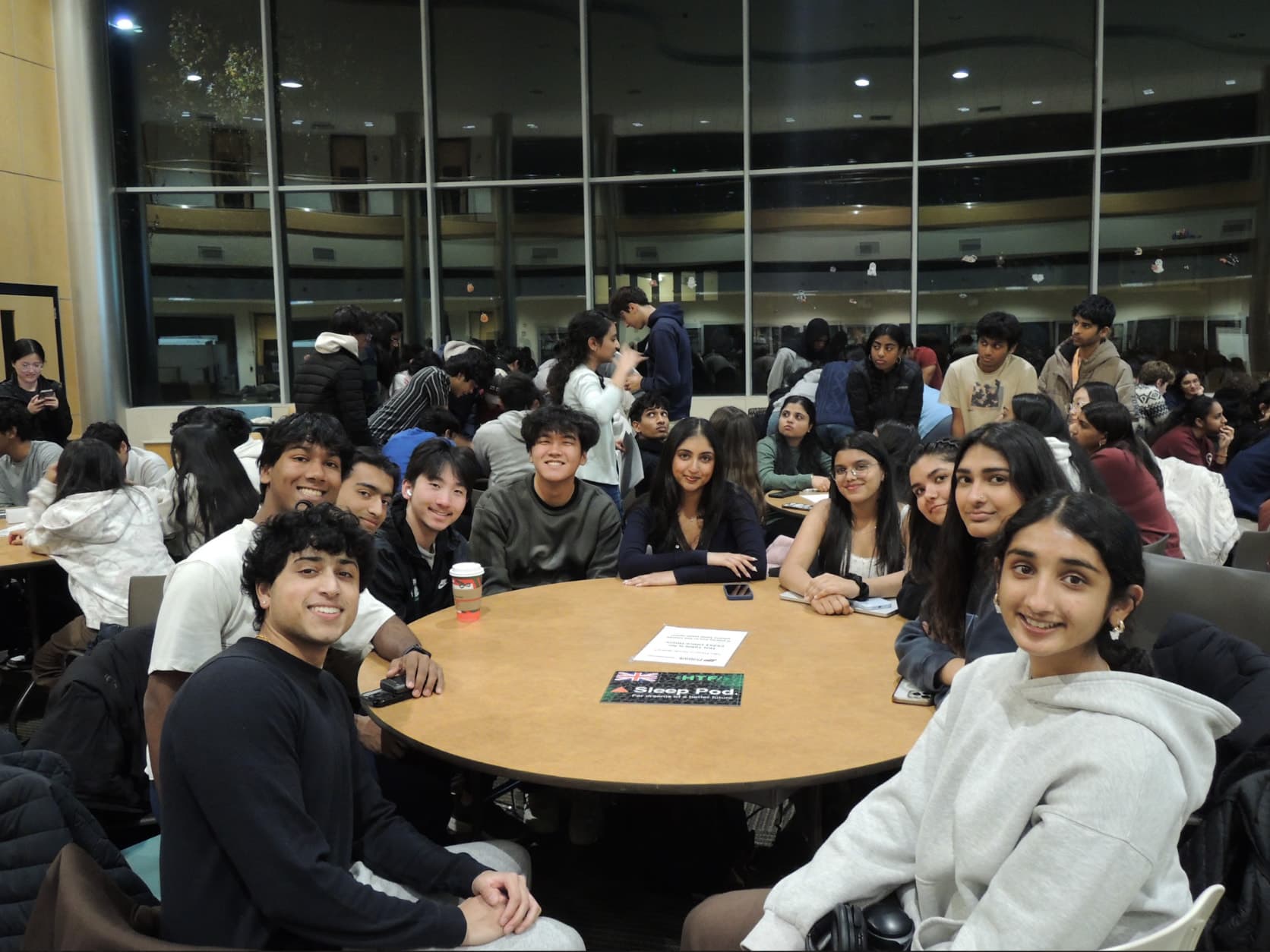 A Hack the Future team gathered around a round table, smiling at the camera